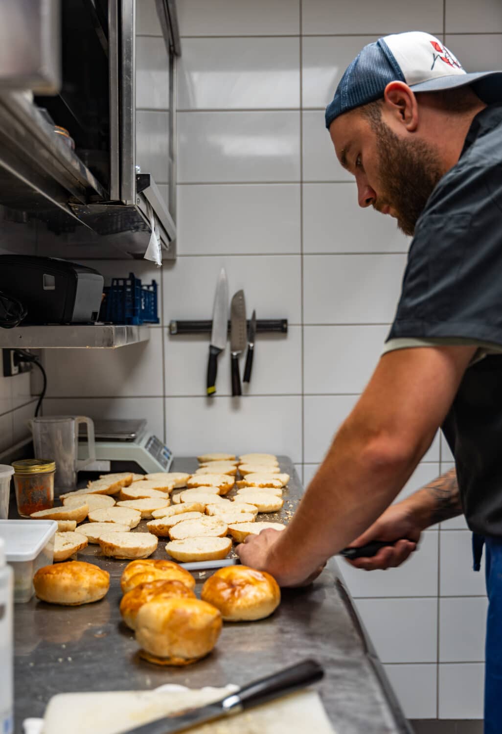 Maxime, membre de l'équipe du restaurant Le Montagnard, préparant des pains à burger en cuisine