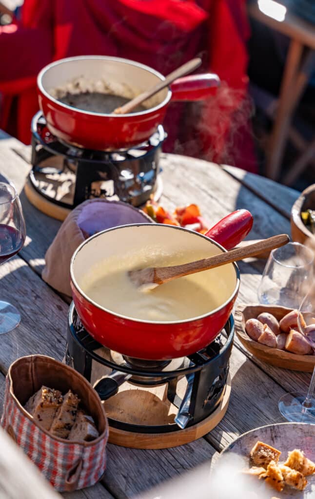 Caquelon de fondue savoyarde au fromage fondu servi en terrasse ensoleillée au restaurant Le Montagnard