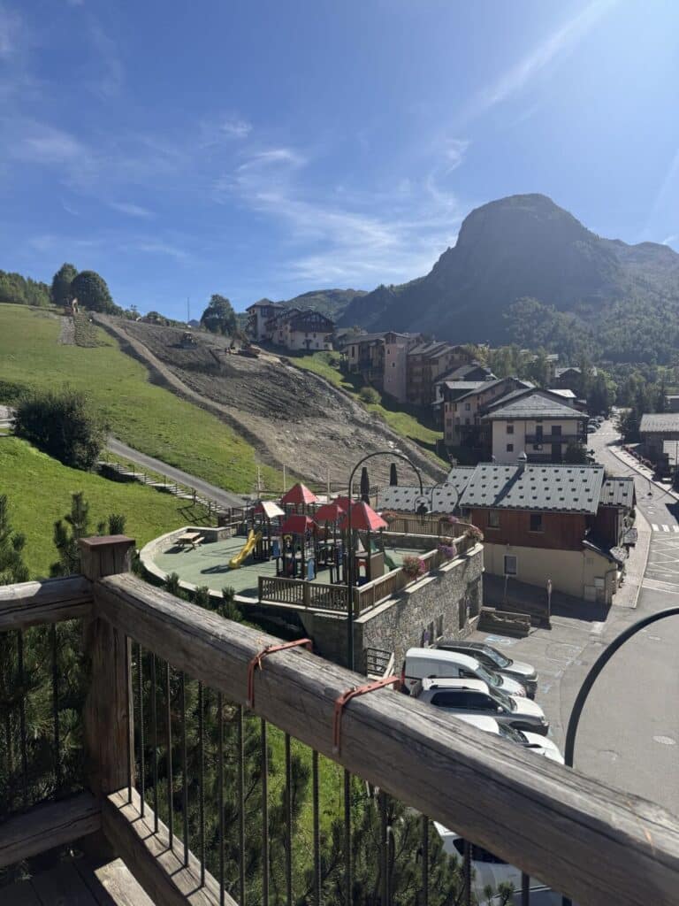 Vue depuis la rebarre de terrasse du restaurant Le Montagnard sur les travaux de terrassement de la piste et le village de Saint-Martin-de-Belleville